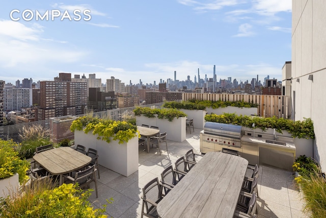 view of patio featuring area for grilling, a view of city, outdoor dining area, and exterior kitchen