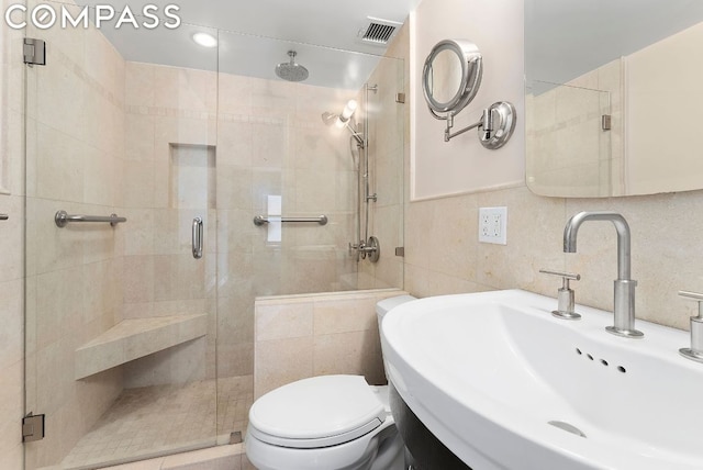 bathroom featuring toilet, tasteful backsplash, walk in shower, and sink