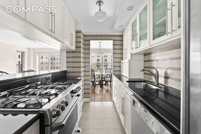 kitchen with appliances with stainless steel finishes, plenty of natural light, light tile patterned flooring, and a sink