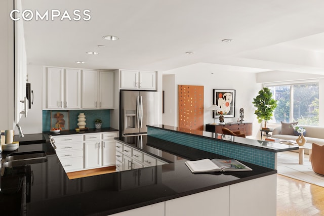 kitchen featuring a sink, dark countertops, white cabinetry, appliances with stainless steel finishes, and decorative backsplash