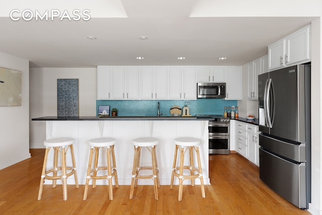 kitchen featuring appliances with stainless steel finishes, white cabinets, and light wood-style floors