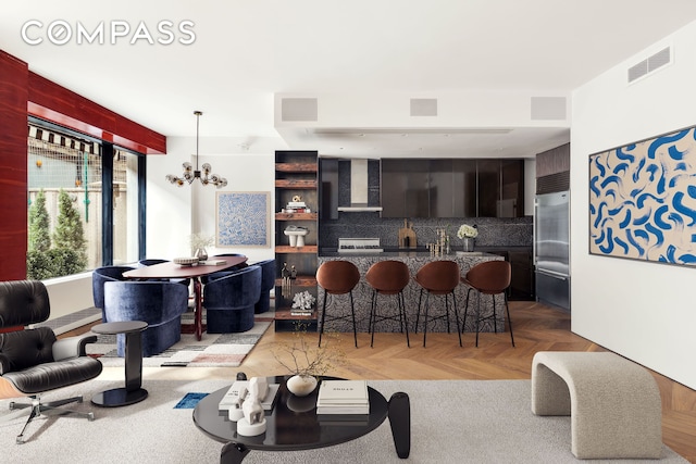 kitchen with visible vents, decorative backsplash, wall chimney range hood, a kitchen bar, and built in fridge