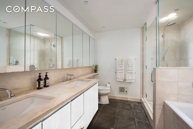 bathroom featuring a stall shower, a sink, backsplash, and toilet