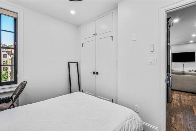 bedroom with dark wood-type flooring and a closet