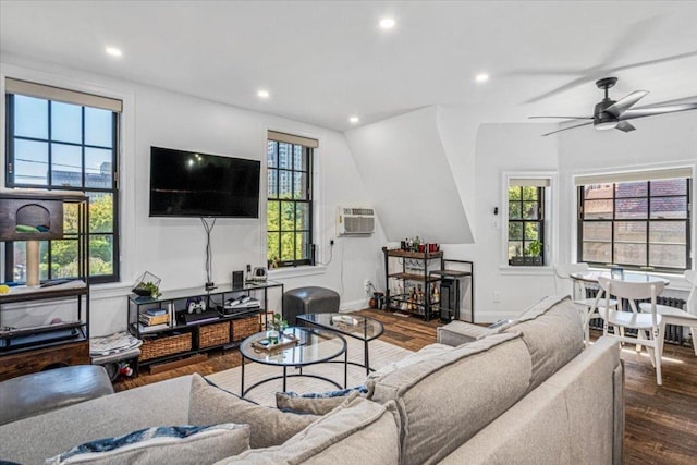 living room with dark wood-type flooring, lofted ceiling, plenty of natural light, and an AC wall unit