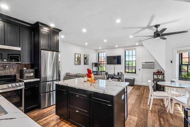 kitchen with a kitchen island, light wood-type flooring, backsplash, stainless steel appliances, and a wall unit AC