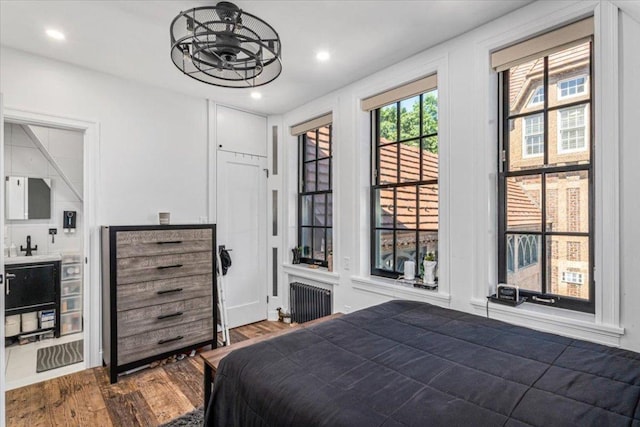 bedroom featuring wood-type flooring, radiator, and access to outside