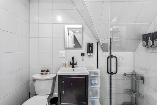 bathroom with tile walls, vanity, a shower with shower door, and toilet