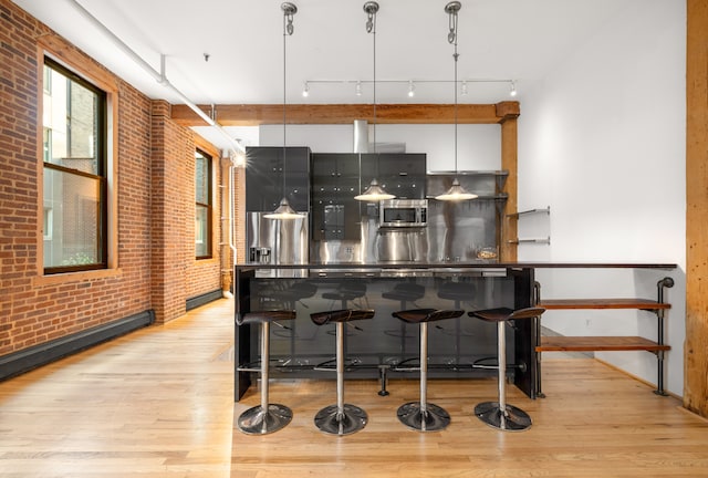 kitchen featuring stainless steel appliances, brick wall, and light wood-style floors