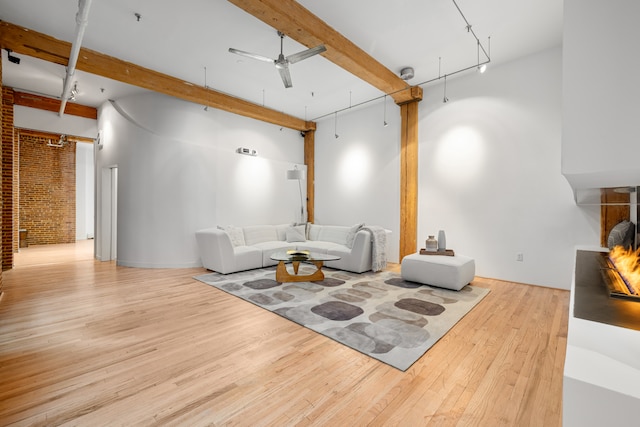 living room with attic access, a ceiling fan, beam ceiling, and wood finished floors