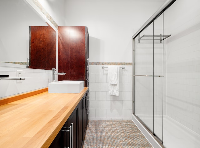 full bath with a stall shower, wainscoting, tile patterned floors, vanity, and tile walls