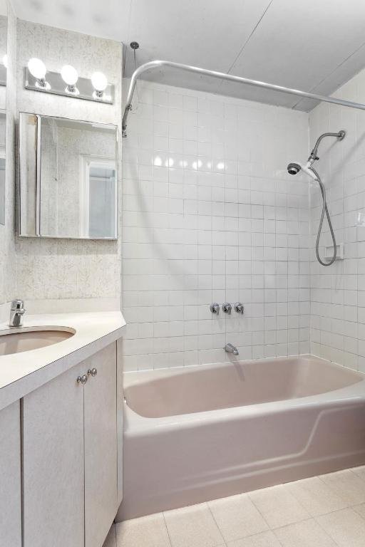 bathroom featuring vanity, tiled shower / bath combo, and tile patterned flooring