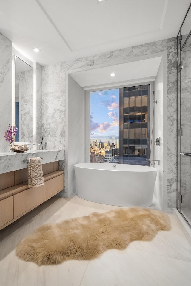 full bathroom with vanity, a soaking tub, stone wall, and a stall shower