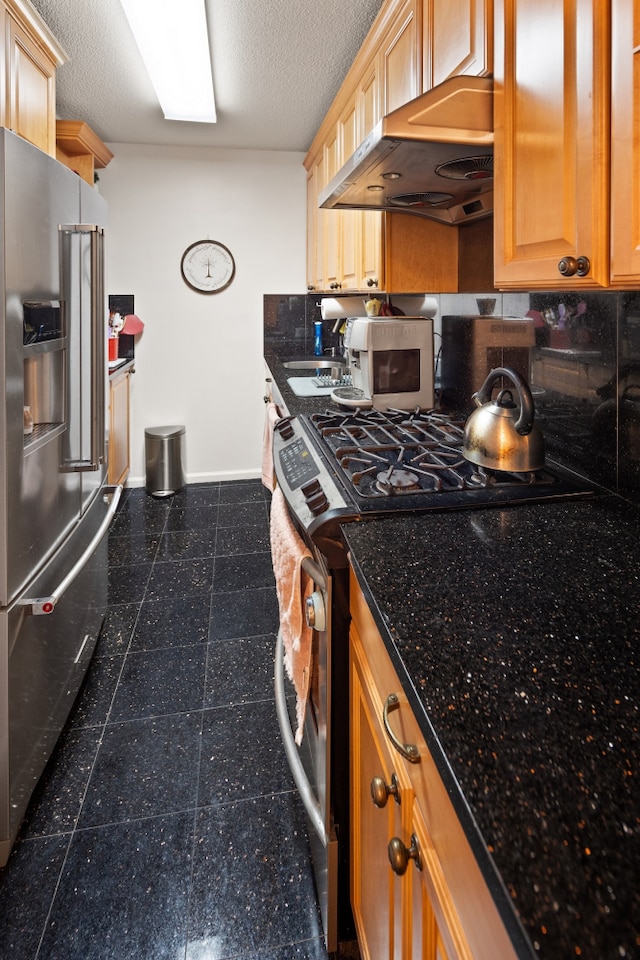 kitchen featuring baseboards, appliances with stainless steel finishes, extractor fan, a textured ceiling, and granite finish floor