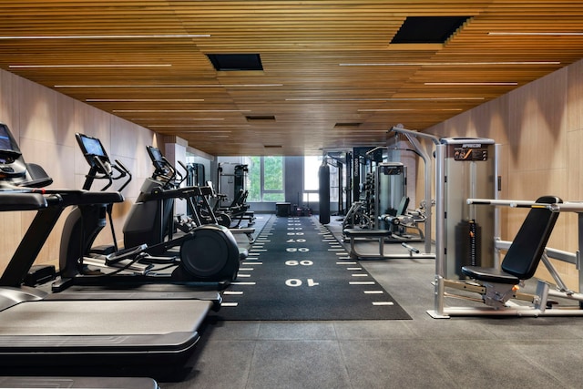 exercise room with wooden ceiling and wood walls