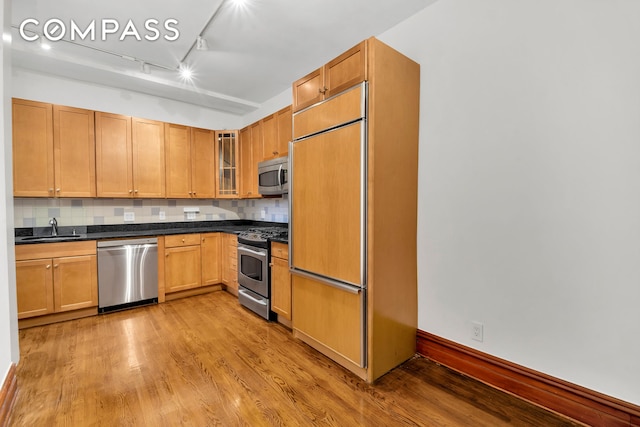 790 Riverside Dr Unit 5F, New York City, NY 10032 - kitchen featuring stainless steel appliances, light wood finished floors, dark countertops, decorative backsplash, and glass insert cabinets
