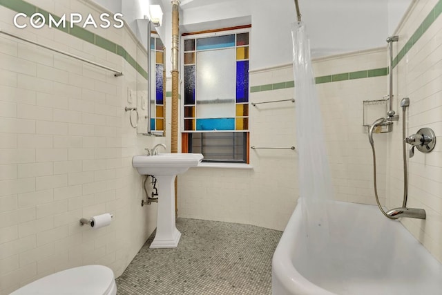 bathroom featuring shower / bath combination with curtain, toilet, tile patterned flooring, and tile walls