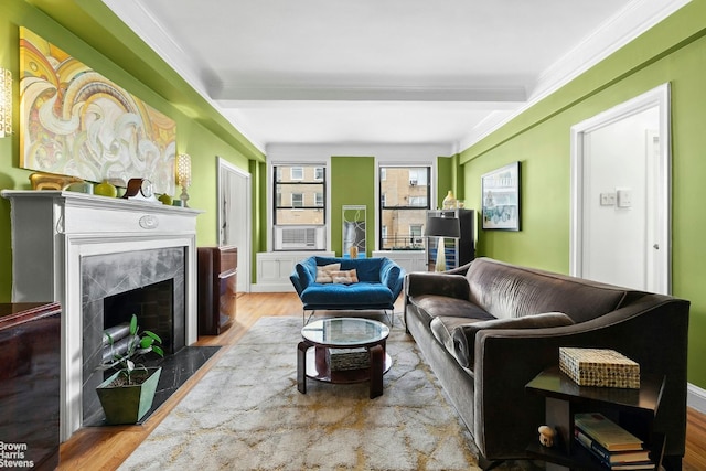 living room featuring beamed ceiling, a premium fireplace, ornamental molding, and hardwood / wood-style flooring