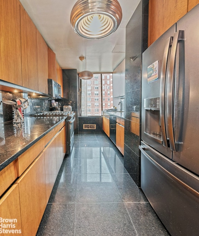 kitchen featuring visible vents, backsplash, granite finish floor, stainless steel appliances, and dark stone counters