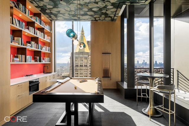 recreation room featuring a city view, floor to ceiling windows, and a wealth of natural light