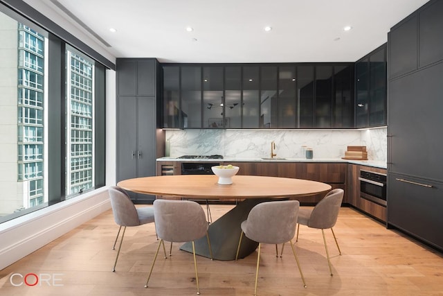 kitchen with light hardwood / wood-style floors, oven, sink, and decorative backsplash