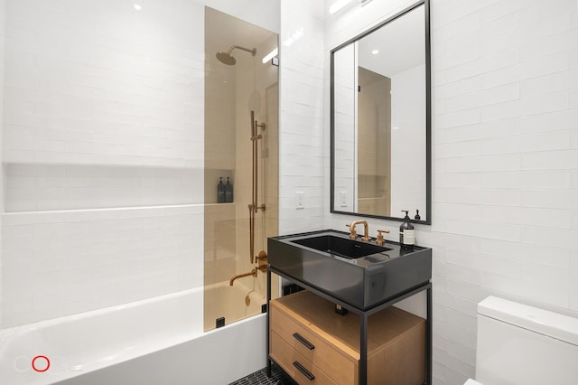 bathroom with tile walls, vanity, toilet, and bathing tub / shower combination