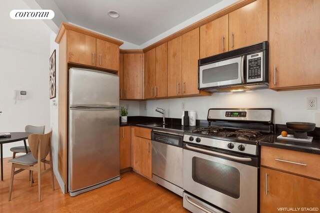 kitchen featuring appliances with stainless steel finishes, sink, and light wood-type flooring