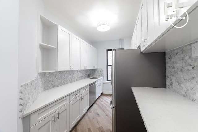 kitchen featuring tasteful backsplash, sink, white cabinetry, light hardwood / wood-style flooring, and stainless steel appliances