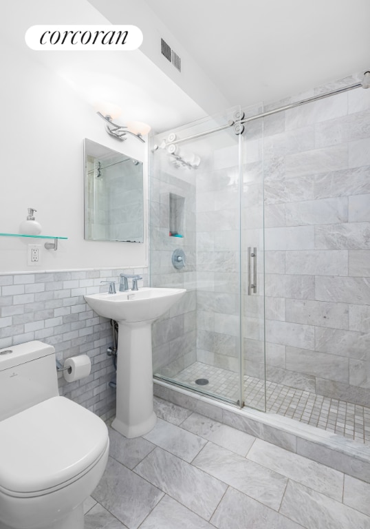 bathroom featuring toilet, tile walls, and walk in shower