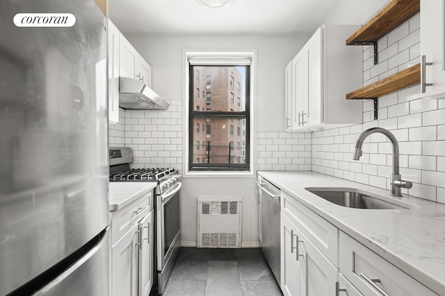 kitchen featuring white cabinetry, appliances with stainless steel finishes, dark tile patterned flooring, light stone countertops, and sink