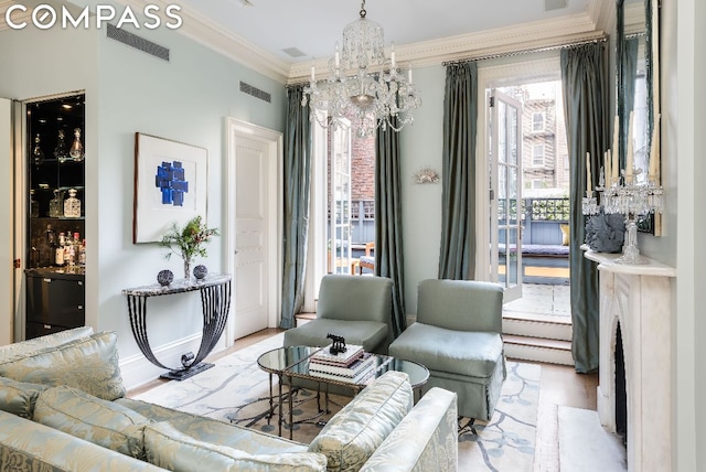 living room with an inviting chandelier, crown molding, and light hardwood / wood-style floors