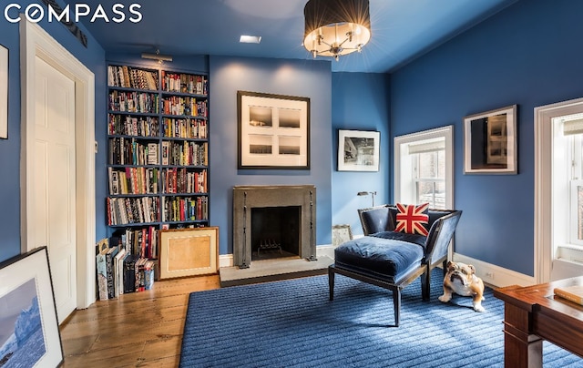 sitting room with an inviting chandelier, hardwood / wood-style floors, and built in features