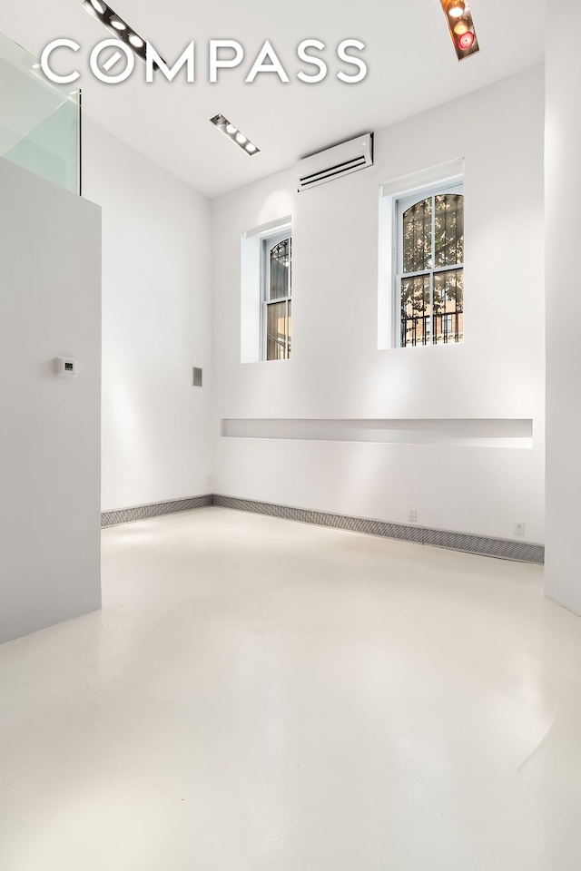 spare room with concrete flooring and a wall unit AC