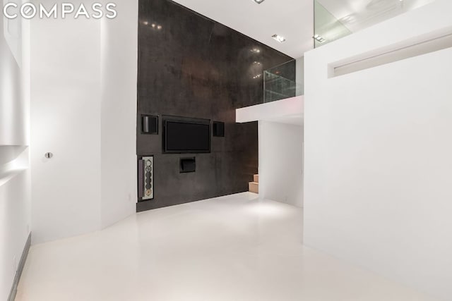 hallway with concrete flooring and a towering ceiling