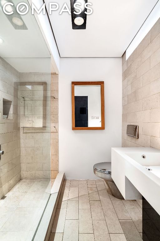 bathroom featuring toilet and tiled shower