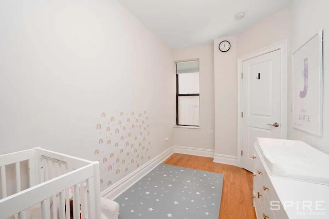 bedroom featuring a nursery area and light hardwood / wood-style flooring