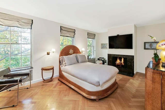 bedroom featuring light parquet floors, a high end fireplace, and multiple windows