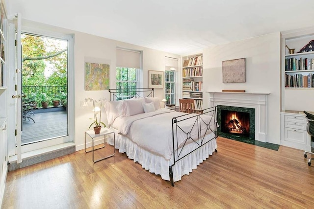 bedroom featuring a high end fireplace and light wood-type flooring