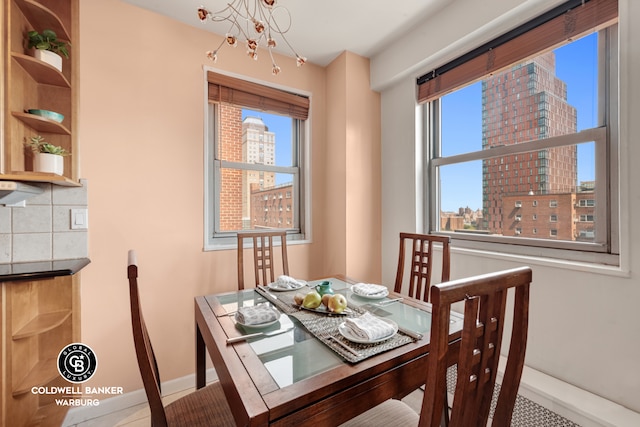 dining area featuring baseboards, a chandelier, and a city view