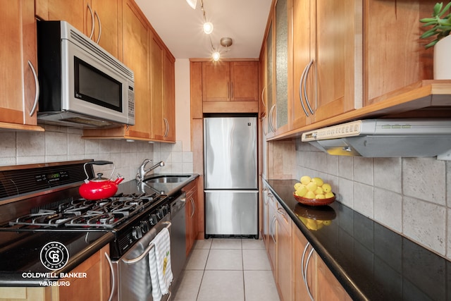 kitchen with a sink, stainless steel appliances, tasteful backsplash, and dark countertops