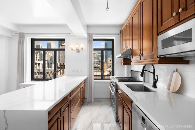 kitchen with appliances with stainless steel finishes, a peninsula, marble finish floor, under cabinet range hood, and a sink