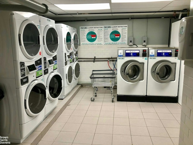 common laundry area featuring stacked washer and dryer, light tile patterned flooring, and washing machine and clothes dryer