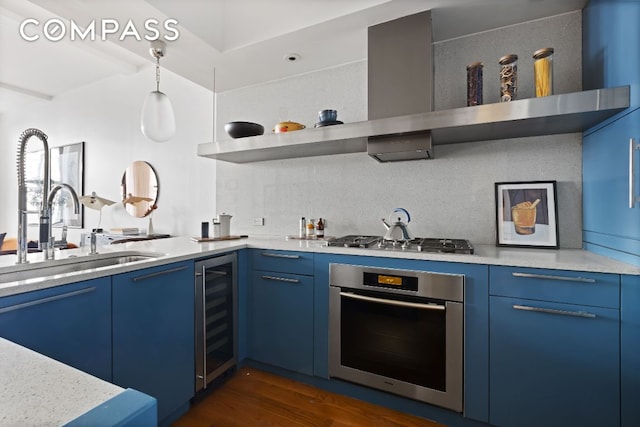 kitchen with wall chimney exhaust hood, wine cooler, blue cabinets, stainless steel appliances, and a sink