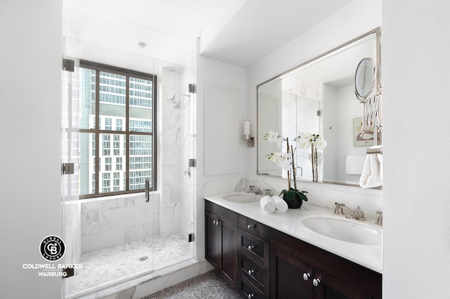 full bath featuring a sink, a marble finish shower, and double vanity