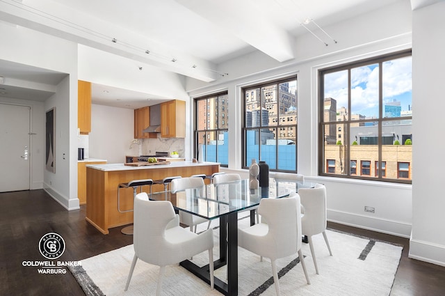 dining room with dark wood finished floors, beamed ceiling, a city view, and baseboards