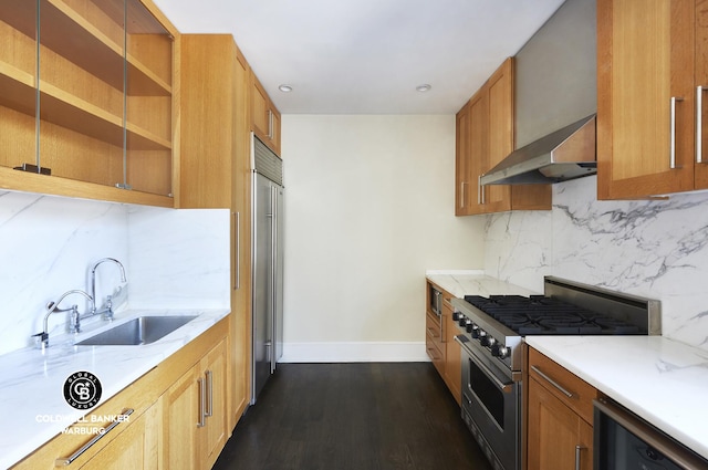 kitchen with backsplash, wall chimney range hood, light stone counters, high end range, and a sink