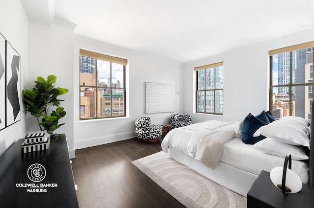 bedroom with crown molding, dark wood-type flooring, and baseboards