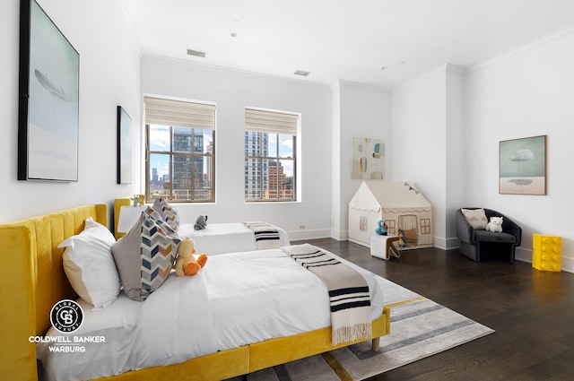 bedroom featuring visible vents, wood finished floors, baseboards, and ornamental molding