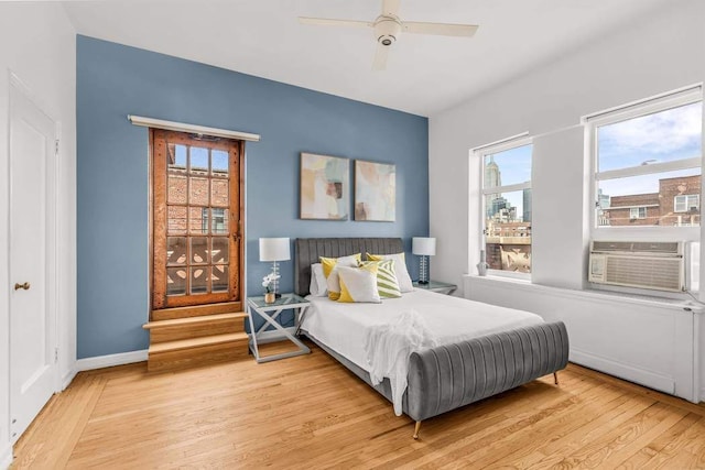 bedroom featuring light wood-type flooring, cooling unit, a ceiling fan, and baseboards