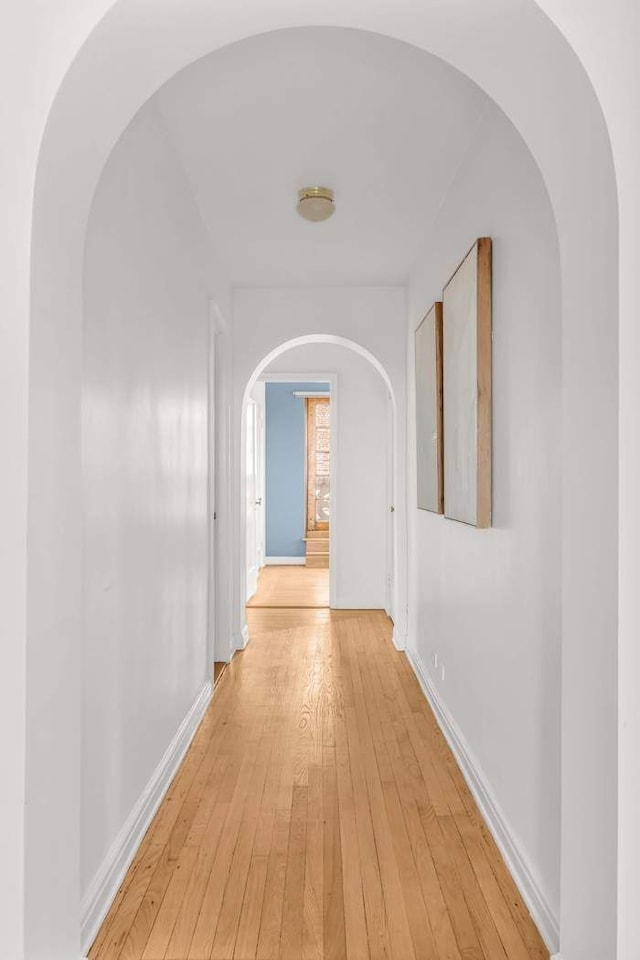 corridor with light wood-type flooring and baseboards